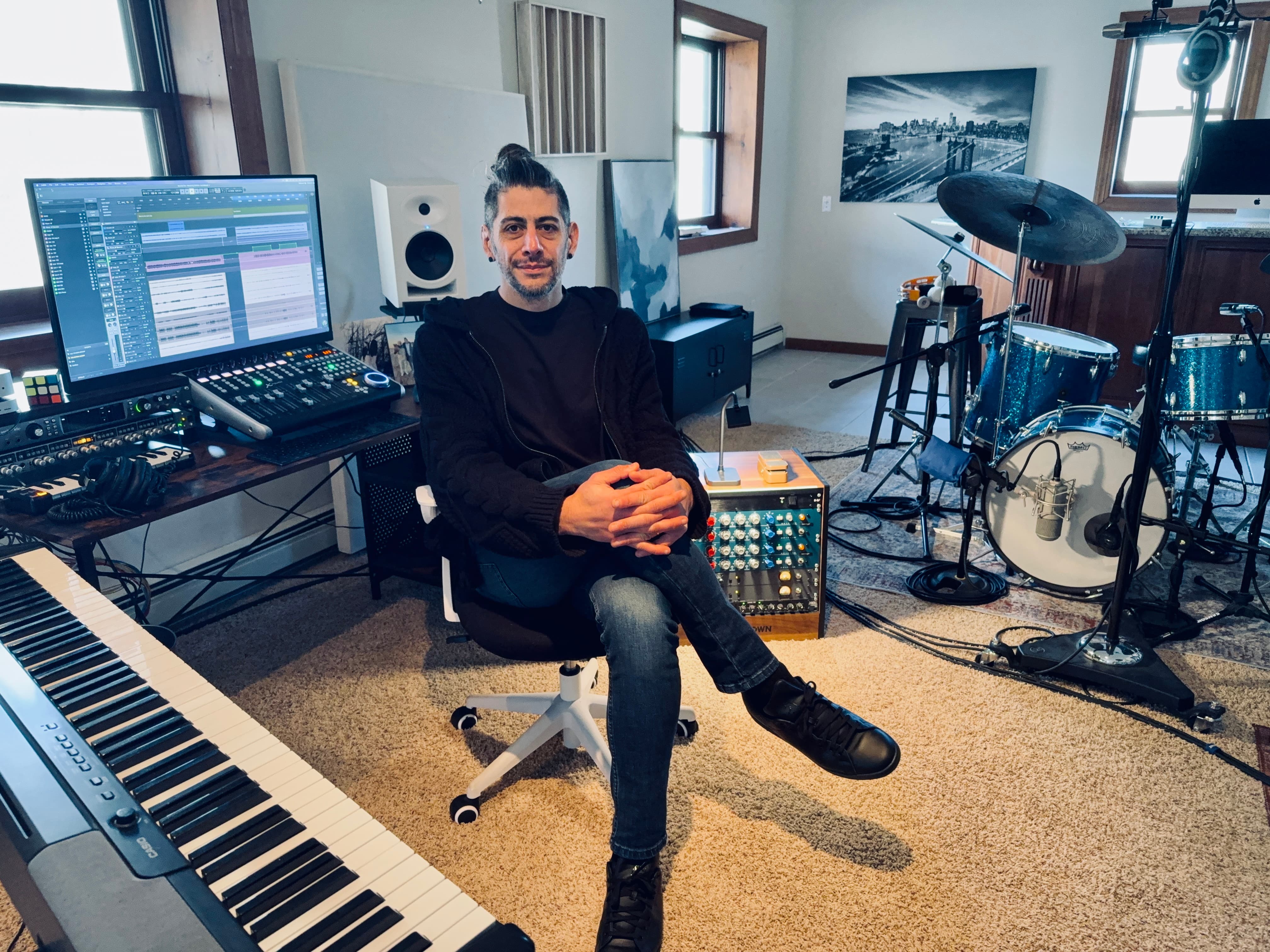 Matias Menarguez seated in his Mount Olive music studio